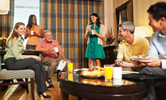 Man Standing Next to an Easel, Presenting to a Small Group in a Hotel Room