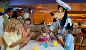 Goofy leads Cast Members and a family in singing happy birthday to a young princess.