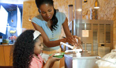 A mom and girl build a yogurt sundae.