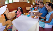 Pluto pals around with families during meal time.