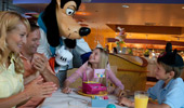 An excited Chef Goofy stops at family's table to share a birthday moment with a young princess.