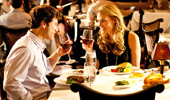 A couple enjoys a fine night out and raises wine glasses to each other.