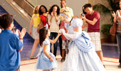 A group of Guests cheer and photograph a young princess as she meets Cinderella.