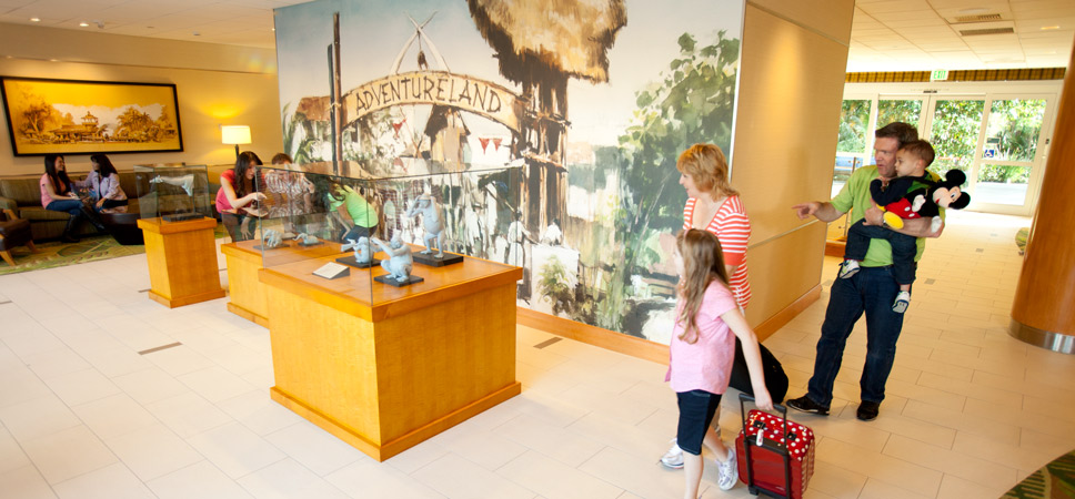 Guests look at character maquettes and statues in glass cases on display in the lobby.