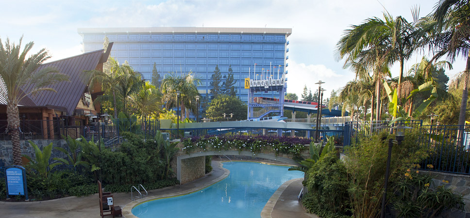 A wide shot of the Disneyland Hotel, one of the 3 pools and the footbridge.