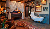 Master bedroom with netted bed, claw-foot tub and luxurious leather easy chairs.