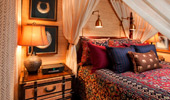Brightly designed bed surrounded by linen drapes.