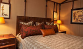 Large bed, surrounded by steamer trunk tables and Adventureland artwork.