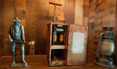 Sculpture of a miner next to a replica of explosives and a miner's lamp.