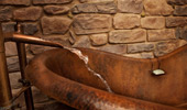 Water filling a free-standing copper-colored tub.