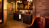 Wide shot of the wash room with 2 sinks, copper-finished tub and shower stall.