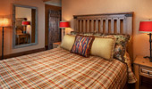 Image of bed decorated with cowboy throw pillows, as seen in a nearby mirror.