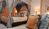 A canopied king bed, an elegant couch and plush pillows.