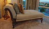 A fainting couch positioned by the expansive windows.