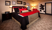 A king-size bed in the master bedroom with a black, cream and red color scheme.