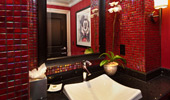 A square sink sits beneath a mirror in a red-tiled bathroom.