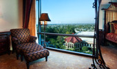 An overstuffed, comfortable chair and free-standing mirror near a large window with an aerial view.
