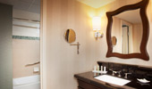 The elegant bathrooms have black granite counters and a large mirror framed by dark wood.