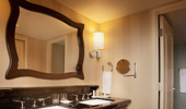 The elegant bathrooms have black granite counters and a large mirror framed by dark wood.