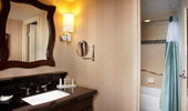 The elegant bathrooms have black granite counters and a large mirror framed by dark wood.