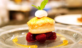 A tower of berries at the base, a light cake, fresh whipped cream and a sprig of mint.