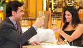 A happy couple raise their glasses of white wine to each other.