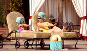 A mother and daughter stretch out on lounge chairs and compare their nails.