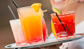 Close up of a server's tray with 5 colorful drinks