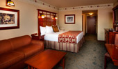 Rich red sofa sits next to a king-size bed in a Standard room with premium view and Club Level services