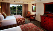 Wide shot of room with 2 queen-size beds and surroundings, like television and glass balcony door