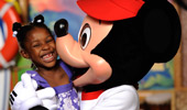 Mickey Mouse gives a girl a kiss on the cheek.