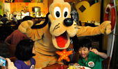 Pluto poses for a silly picture with 2 young Guests.