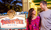 A couple stand by the sign: Disney's Paradise Pier Hotel