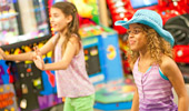 2 girls play an arcade game.