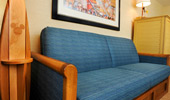 A surfboard-inspired drink table stands next to a plush couch.