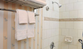 Shot of the shower with a sea wave tile detail and surfboard-themed curtain